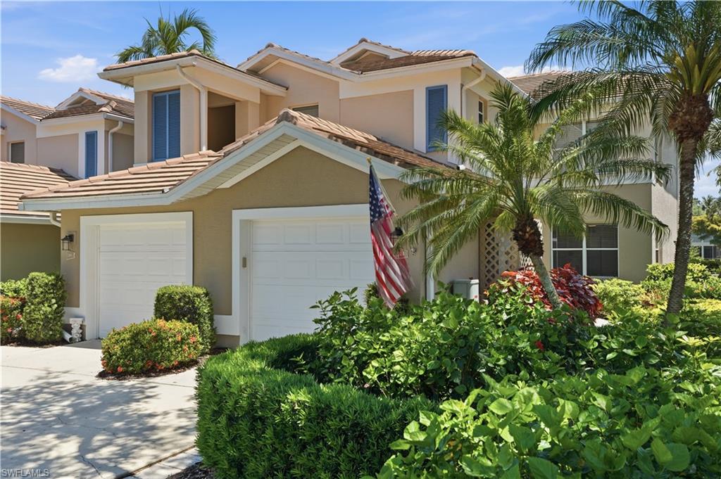 Stucco exterior featuring dual garage doors, a tile roof, and dormer windows
