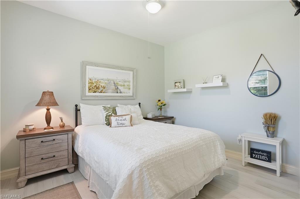 Spacious room featuring light-toned walls, wood-finish flooring, a ceiling-mounted light fixture, and white baseboards