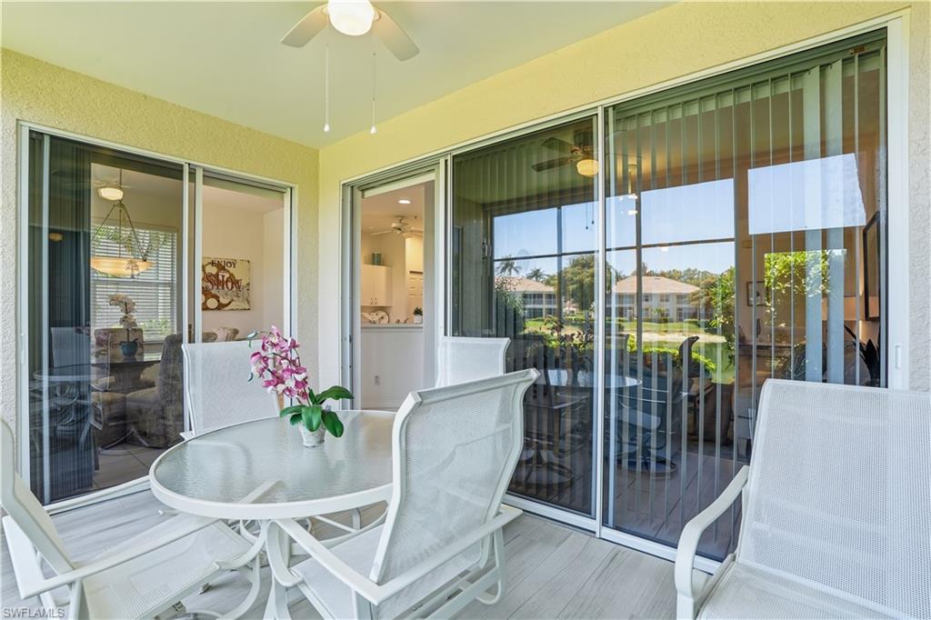 Screened lanai featuring textured walls, a ceiling fan, and multiple sliding glass doors with vertical blinds
