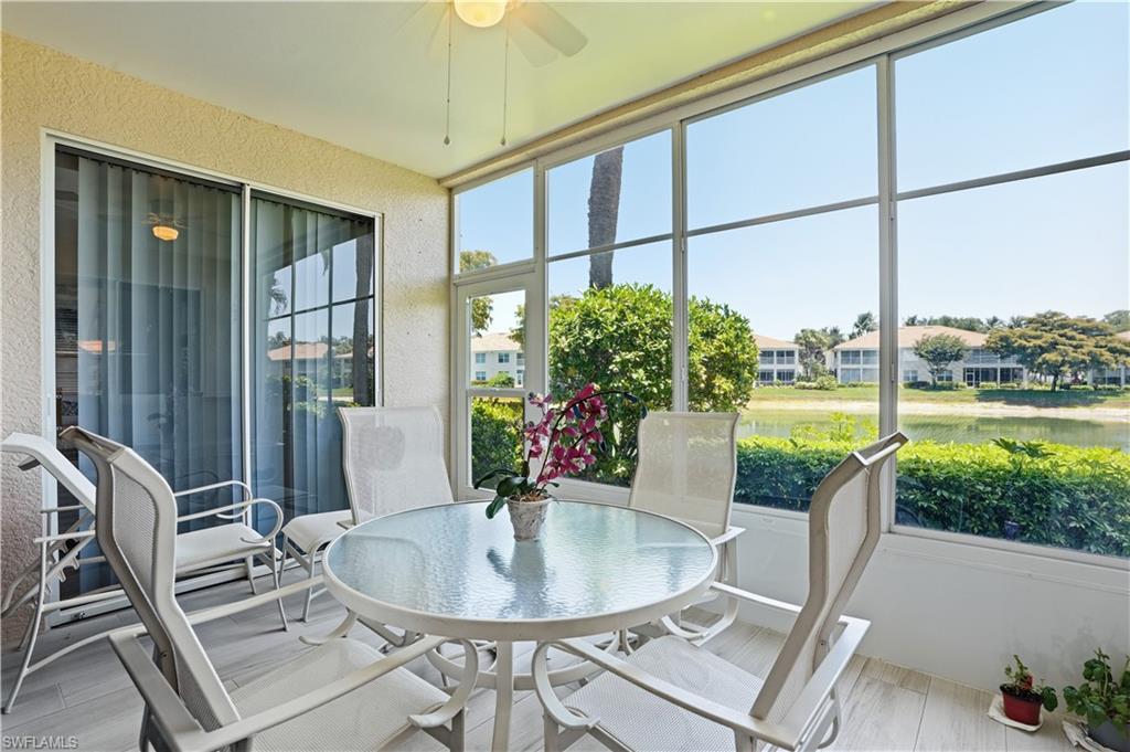 Screened lanai featuring large windows, a ceiling fan, and sliding glass door access, all overlooking a body of water with established landscaping