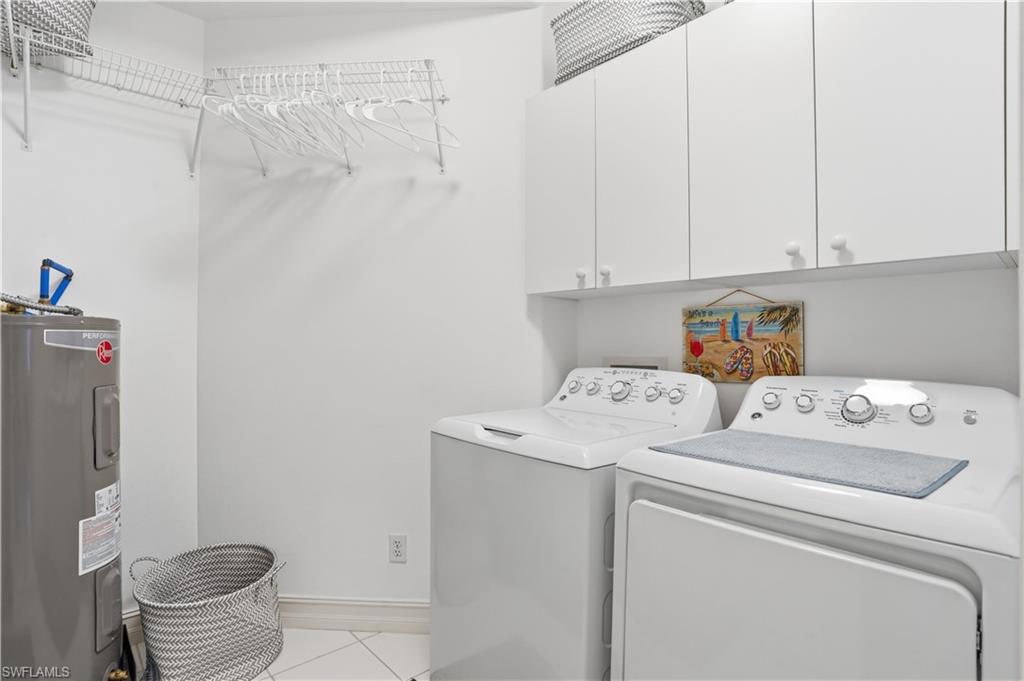 Dedicated laundry area featuring white upper cabinetry, wire shelving, and a water heater