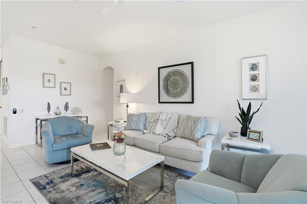 Spacious living area featuring white tile flooring, neutral wall tones, and a recessed archway