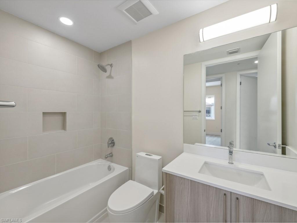 Bathroom featuring a single vanity with light wood-finish cabinetry and a light-colored solid surface countertop