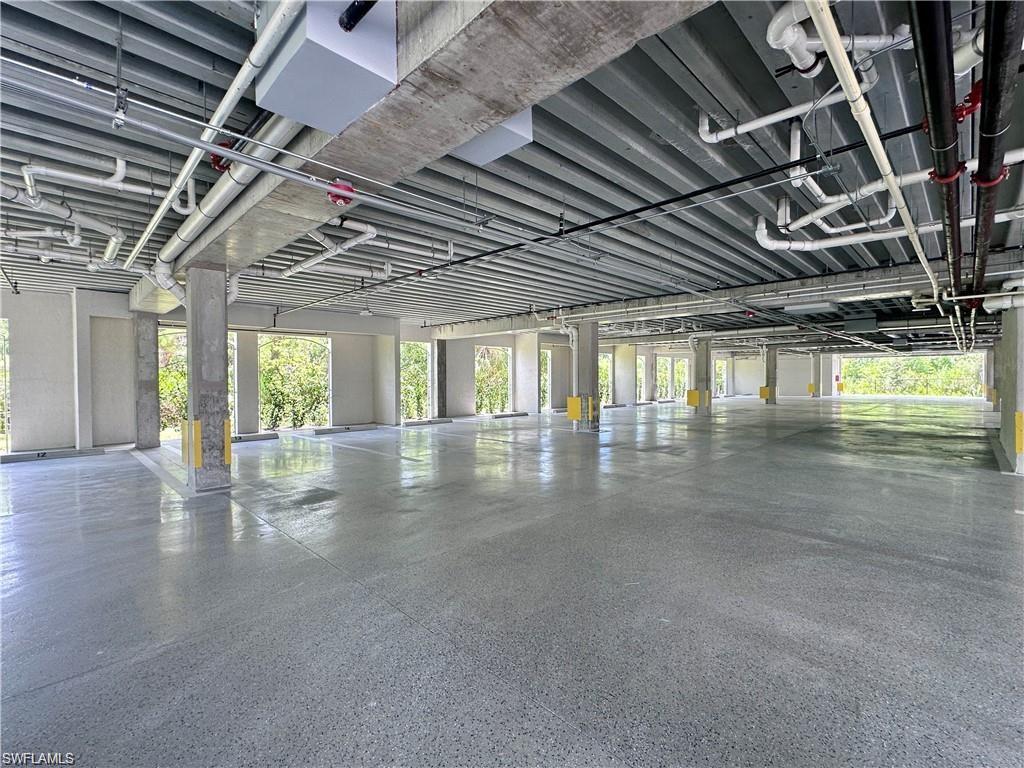 Spacious open-air parking structure featuring an exposed concrete ceiling, polished concrete flooring, and multiple support columns
