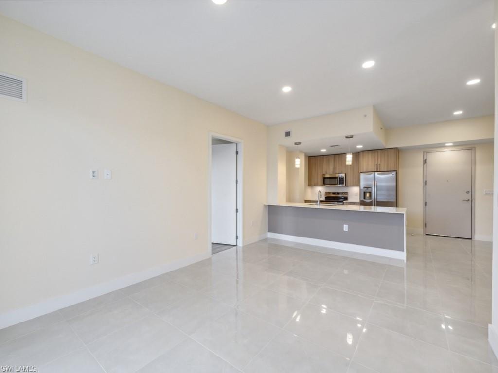 Open concept living area featuring light-toned walls and glossy tile flooring