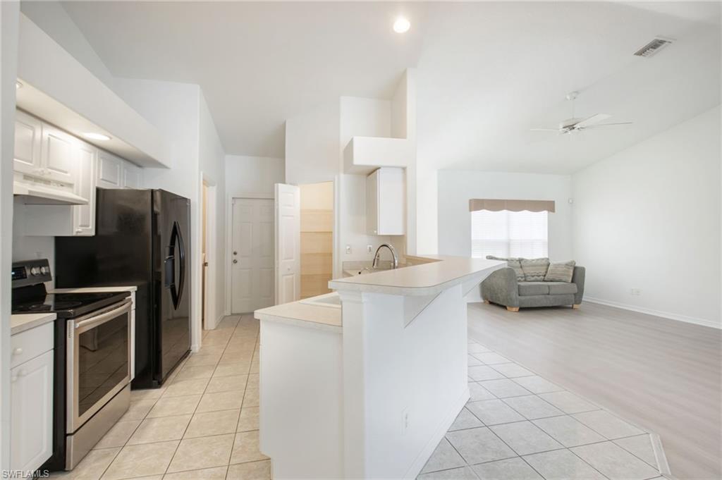Open-concept living area featuring a kitchen with white cabinetry and stainless steel appliances