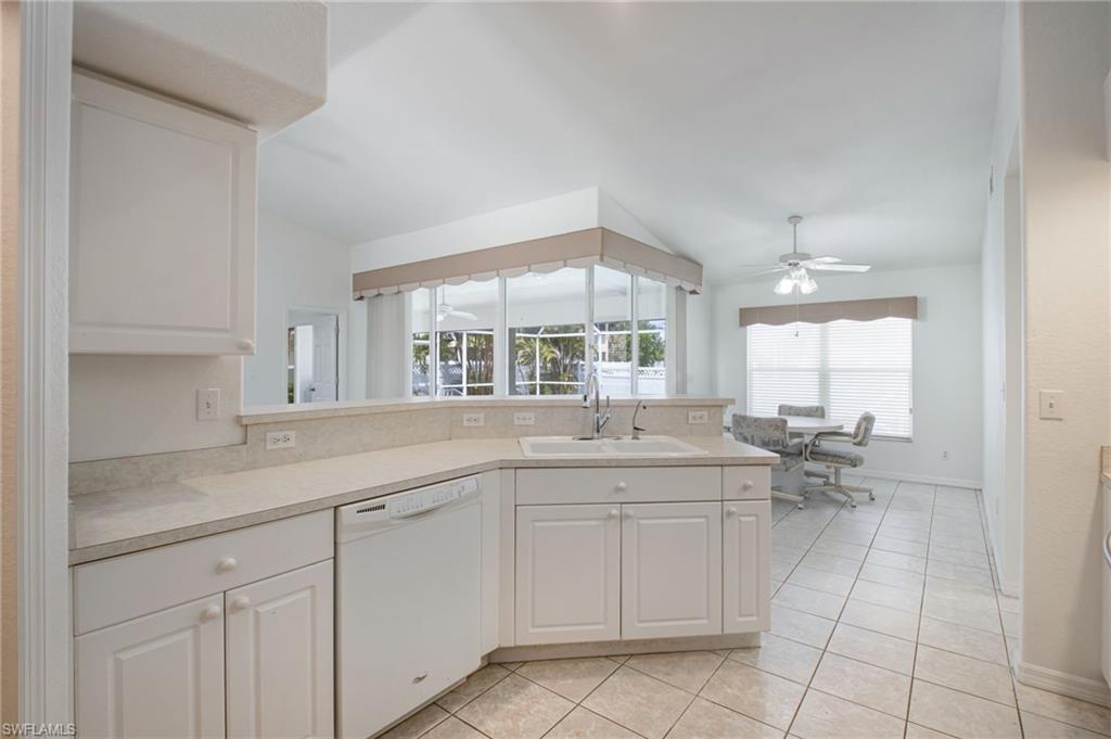 Bright kitchen featuring white cabinetry, light-toned countertops, integrated dishwasher, and a double basin sink