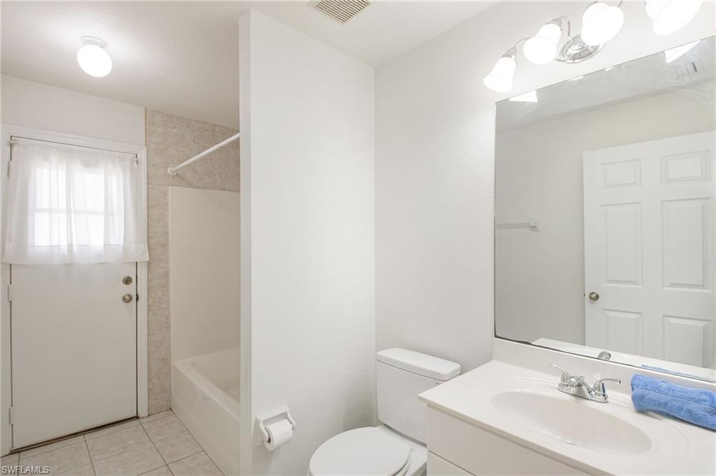 Bathroom featuring a single vanity with an integrated sink, a large wall-mounted mirror, and a full-size bathtub with a shower kit