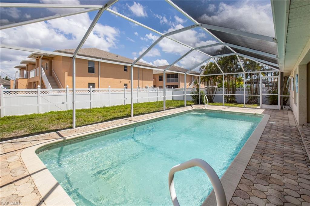 Screened-in swimming pool featuring a curved entrance, pool steps, and surrounding paver decking