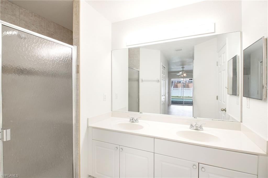 Bathroom featuring a dual vanity with built-in sinks, a large wall-mounted mirror, and a glass-enclosed shower with tiled walls