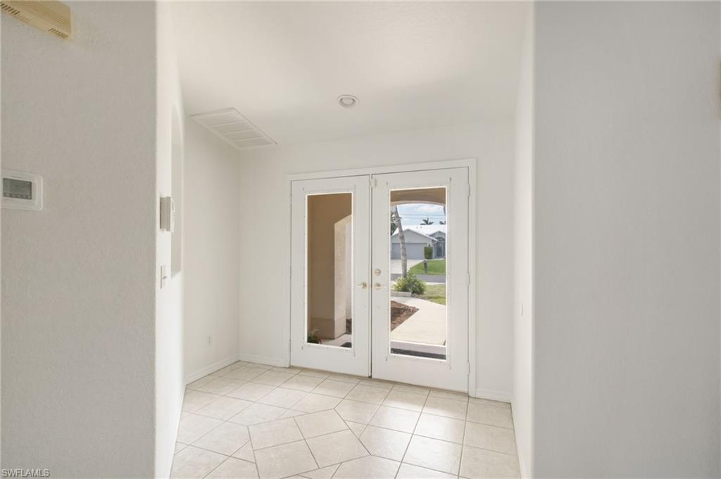 Entryway featuring double glass-panel doors, hexagonal tile flooring, recessed ceiling lighting, and a visible thermostat