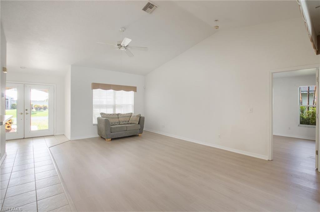 Spacious room featuring vaulted ceilings, light wood-finish flooring, and a ceiling fan