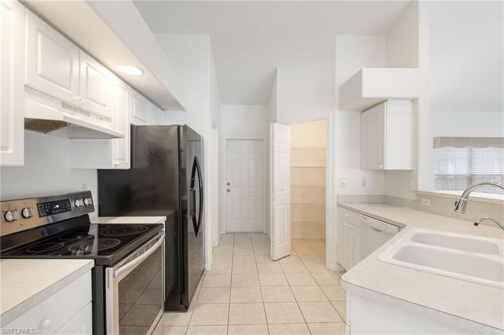 Galley kitchen featuring white cabinetry, light-toned countertops, and tile flooring