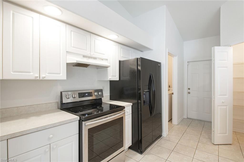 Kitchen featuring white cabinetry, light-toned countertops, a stainless steel range, and a black refrigerator