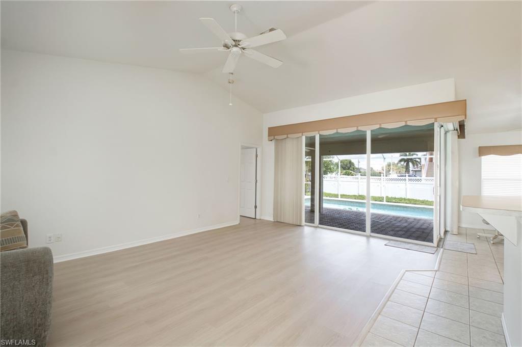 Spacious living area featuring light wood-finish flooring, vaulted ceilings, and a ceiling fan
