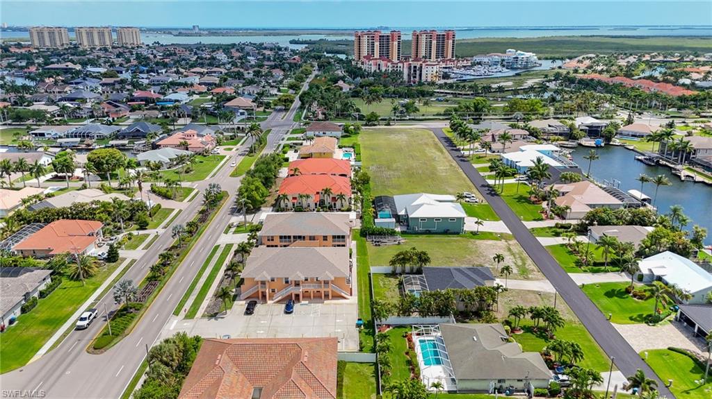 Expansive aerial capturing a suburban area with a mix of residential properties, undeveloped land parcels, and waterfront properties