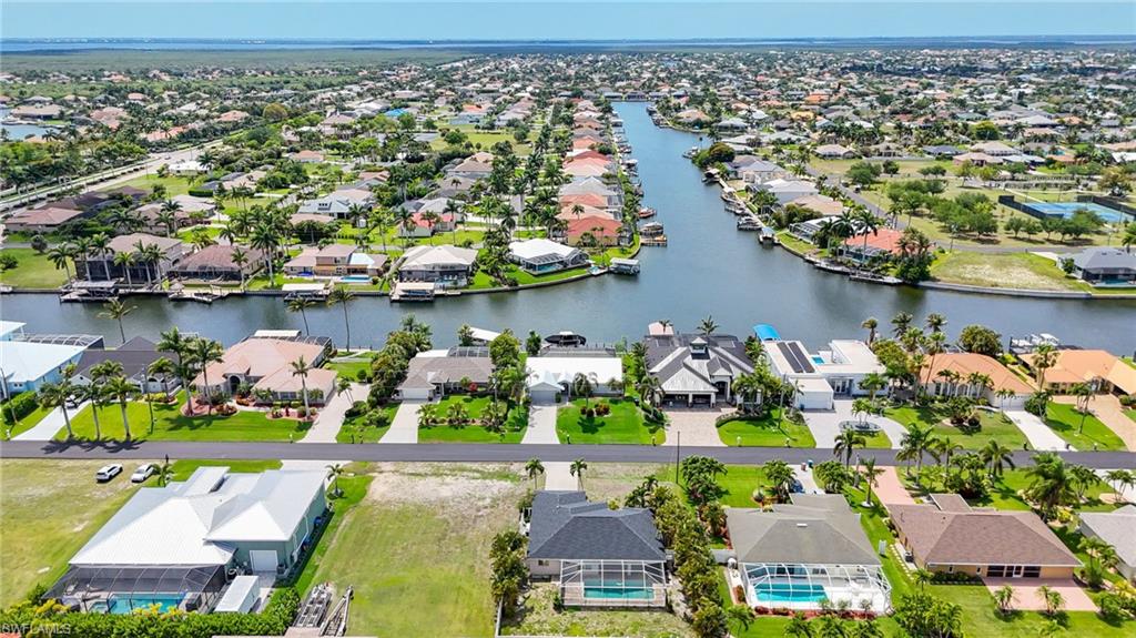 Waterfront community featuring canal access, mature palm trees, manicured lawns, and diverse architectural styles