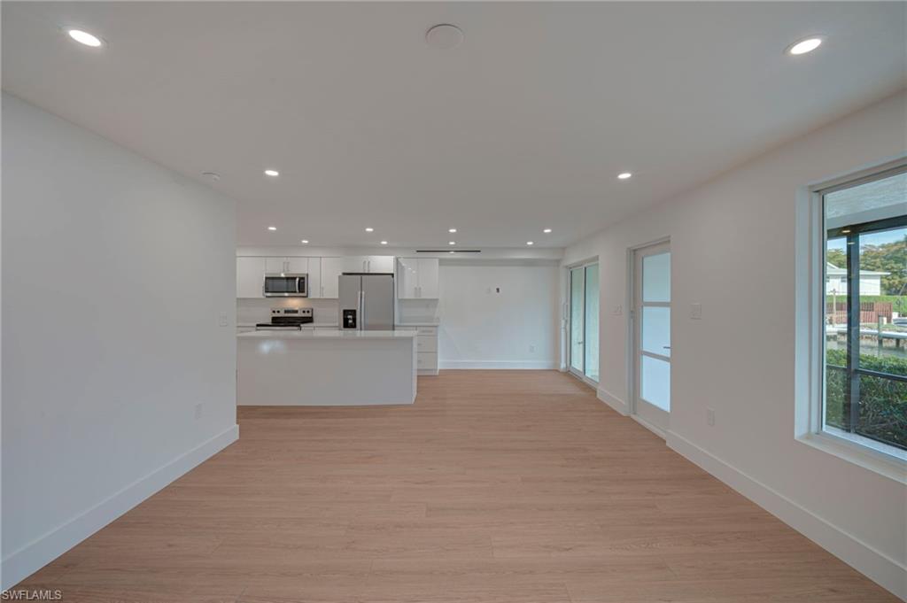 Open-concept living area featuring wood-finish flooring, recessed lighting, and white walls