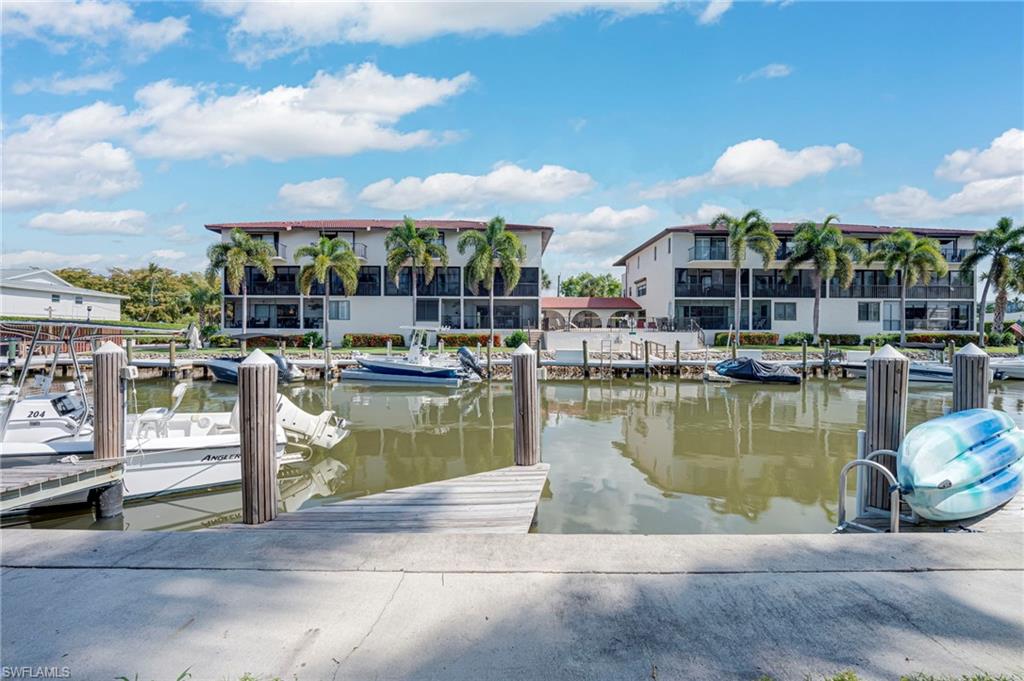 Waterfront property featuring dock access with multiple boat slips, two multi-story buildings, and mature palm trees