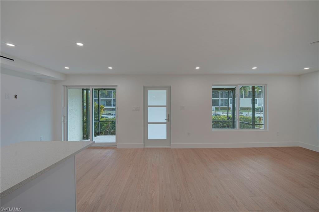 Open-concept living space with light wood-finish flooring, recessed lighting, and white walls