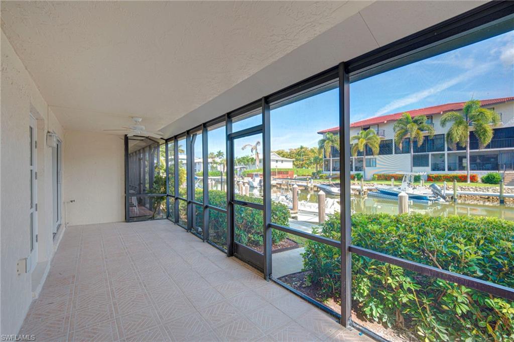 Screened patio featuring tiled flooring, a ceiling fan, and direct water access with boat docks