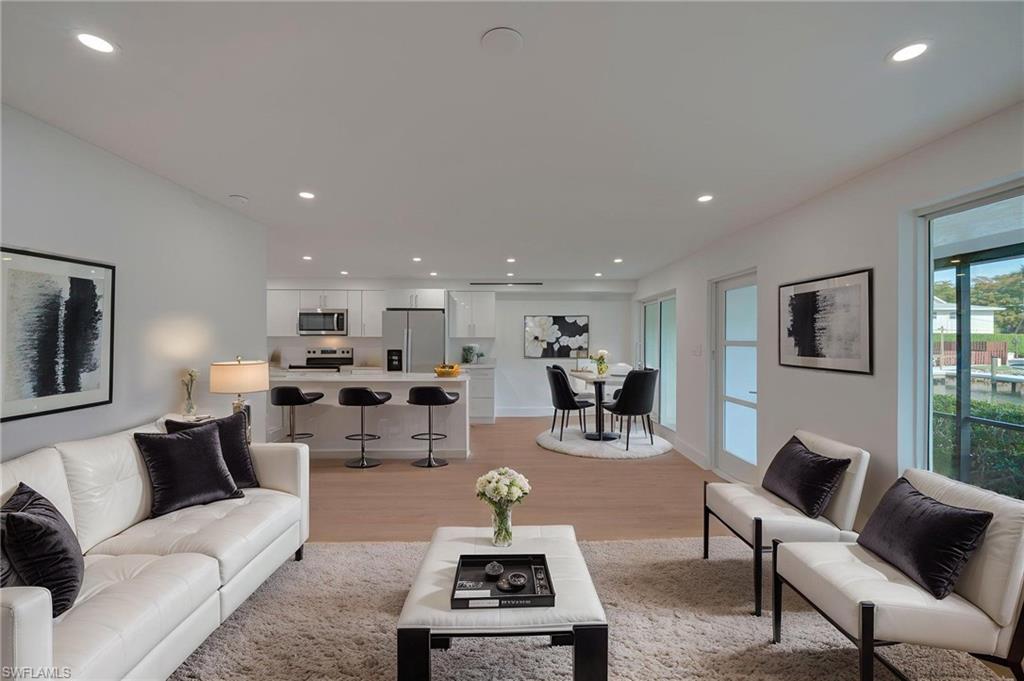 Open-concept living area with light wood-finish flooring, recessed lighting, and expansive windows