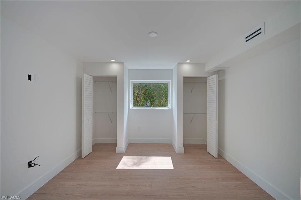 Bright room featuring light wood-finish flooring, recessed lighting, and a window with exterior tree views