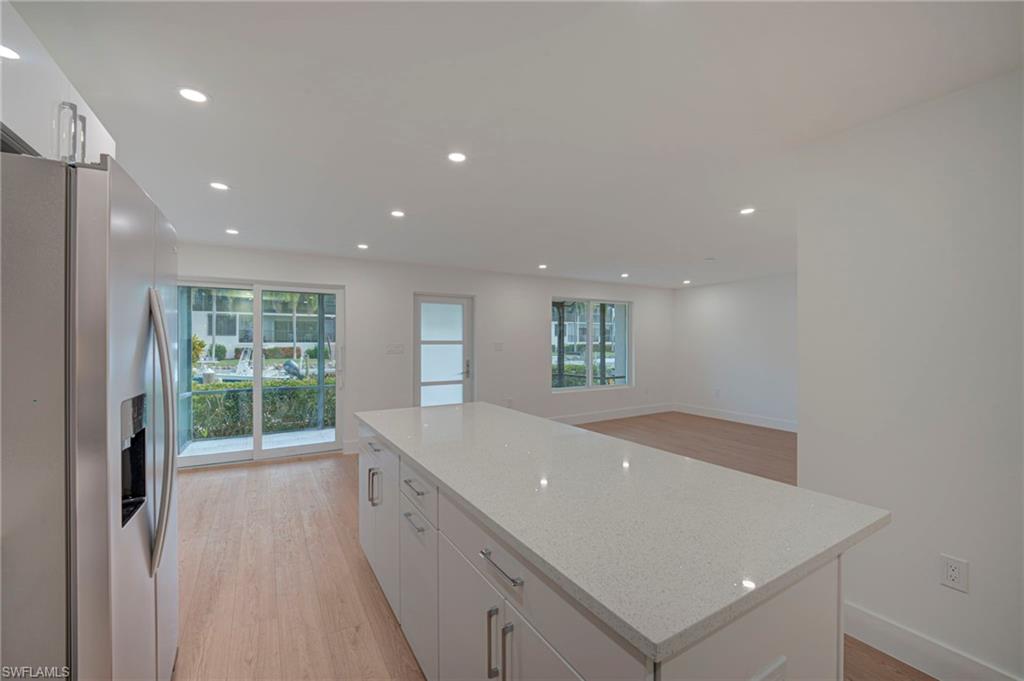 Kitchen island featuring a light-toned countertop and white cabinetry with stainless steel pulls