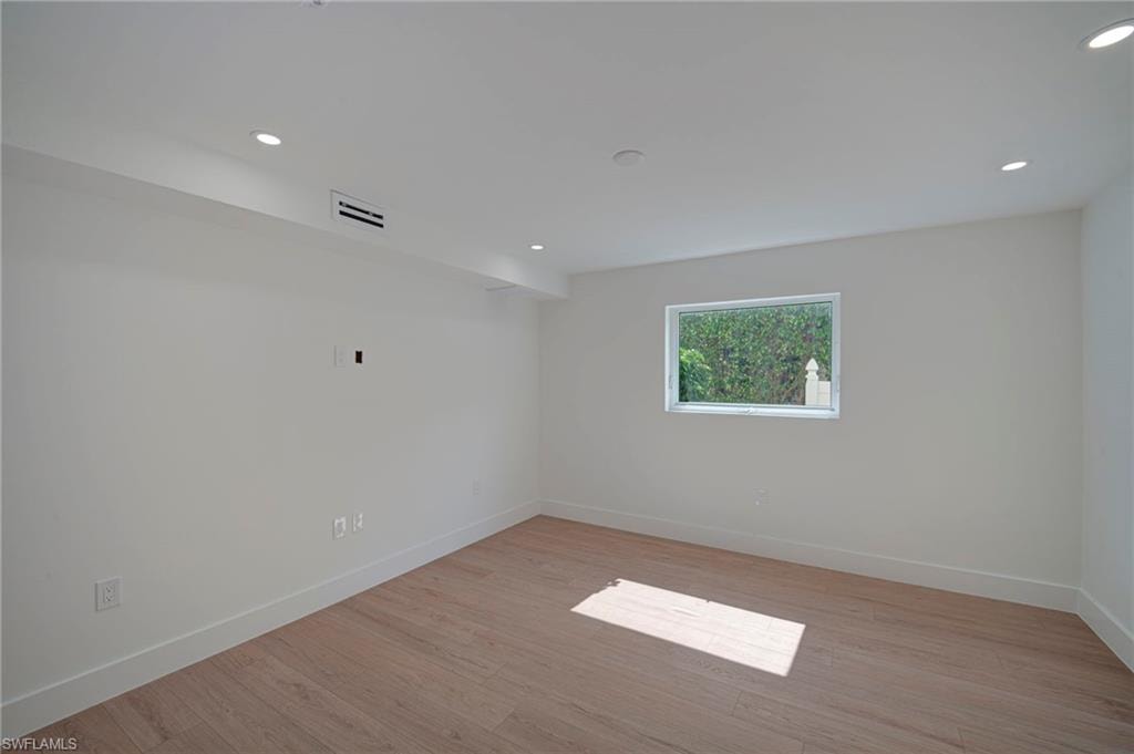 Bright interior space featuring light wood-finish flooring, recessed lighting, a single window, and white baseboards