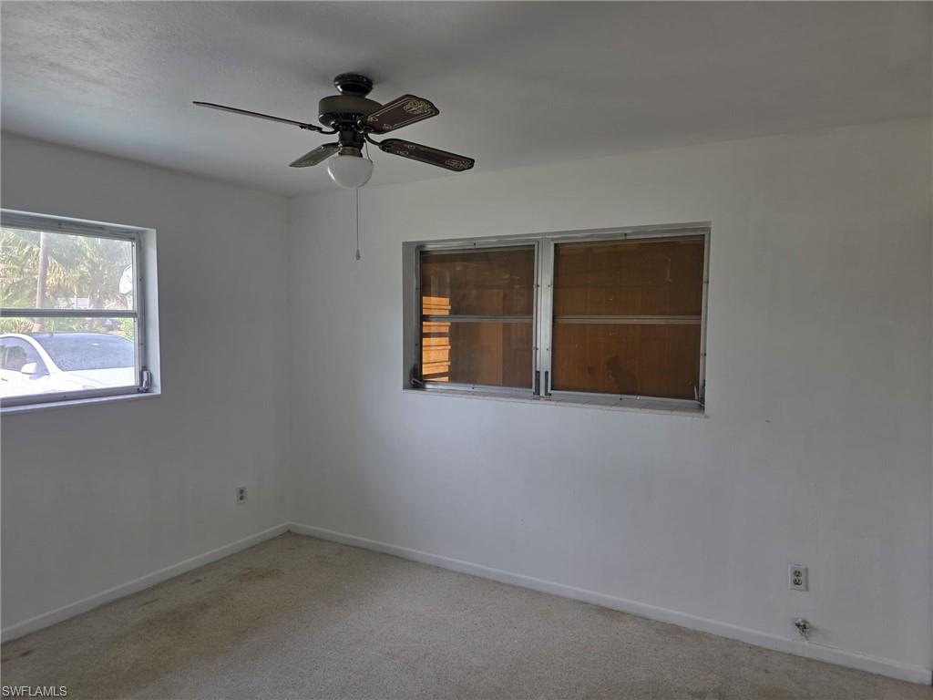 Room featuring two windows, a ceiling fan with light fixture, and wall-to-wall carpeting