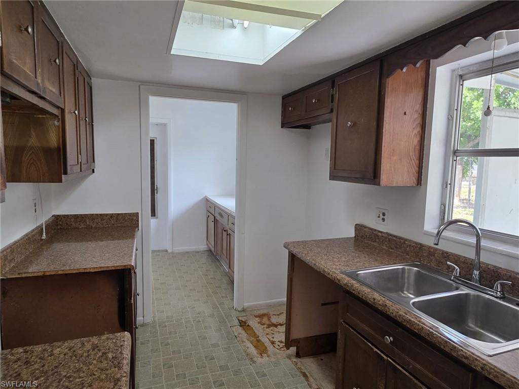 Kitchen featuring a dual basin stainless steel sink with chrome faucet, wood-finish cabinetry, and speckled countertops