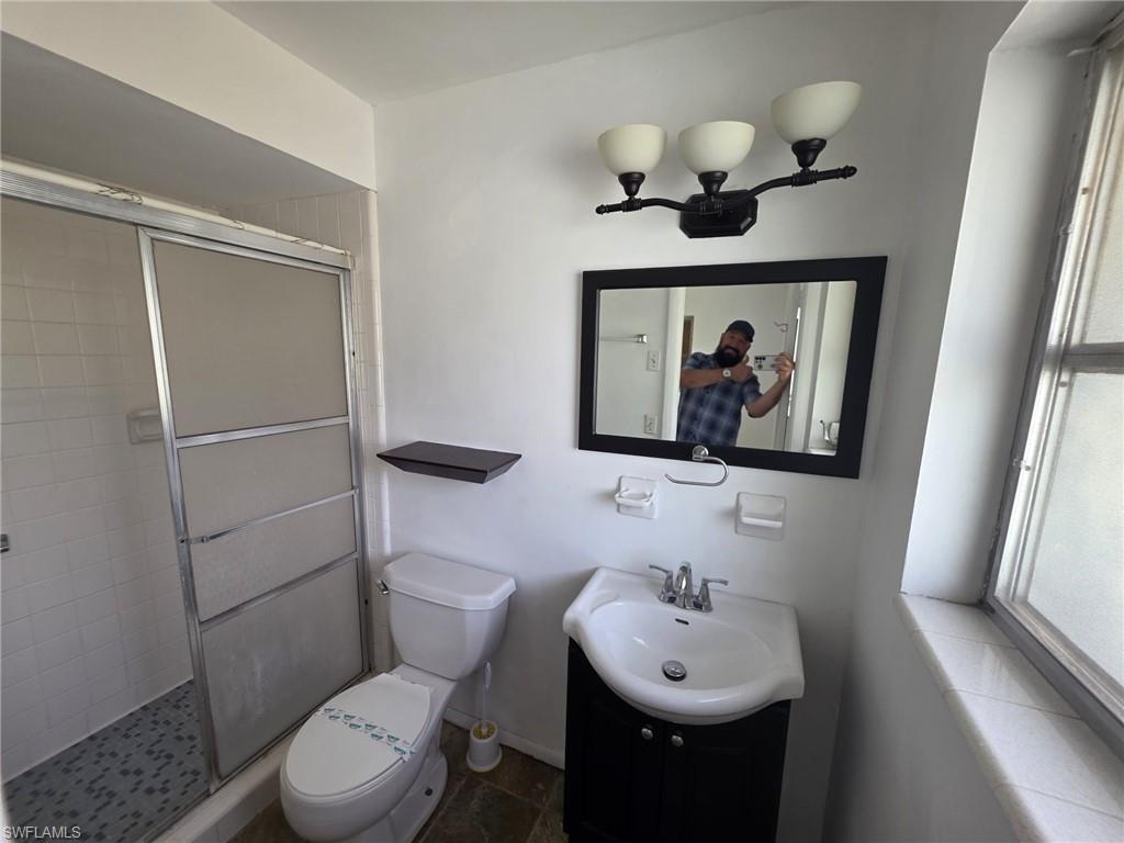 Bathroom featuring a vanity with an integrated sink, a rectangular framed mirror, and a three-light fixture
