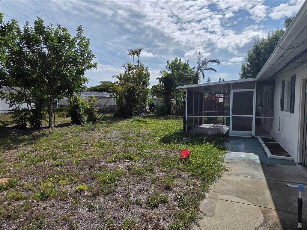 Expansive backyard featuring a screened porch, concrete patio, and mature trees