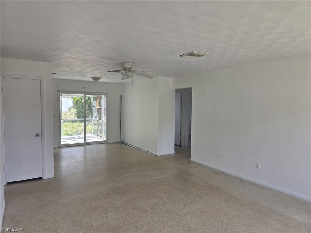 Expansive open-concept room featuring light-toned flooring, white walls, and a ceiling fan