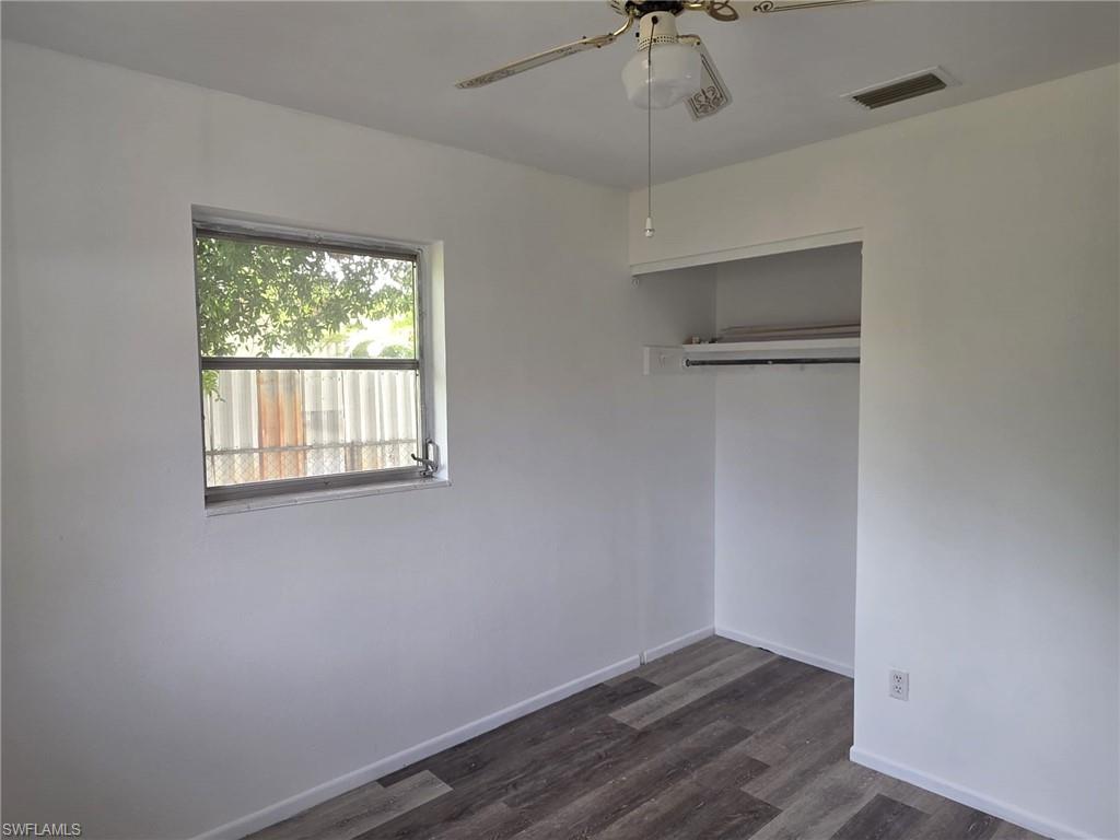 Room featuring wood-finish flooring, white walls, and a ceiling fan with integrated lighting