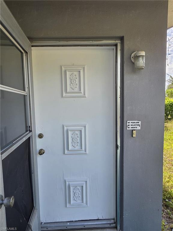 White entry door featuring decorative paneling and brass-tone hardware