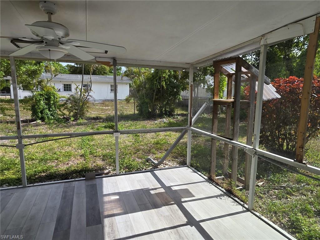 Screened patio with multi-tone wood-finish flooring, white ceiling fan, and backyard access