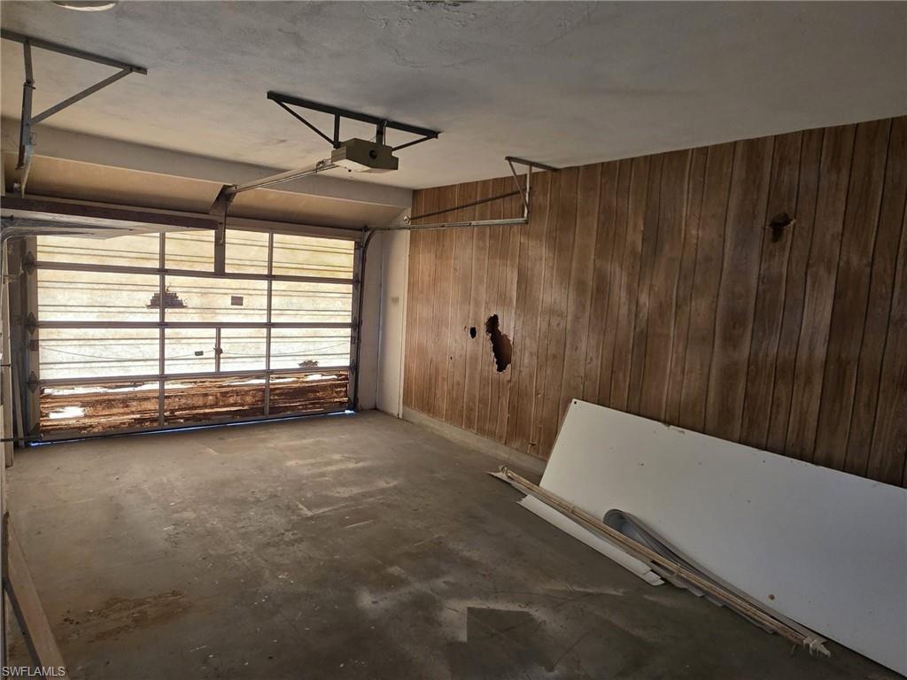 Garage space featuring a paneled wood-finish wall and a clear panel overhead door