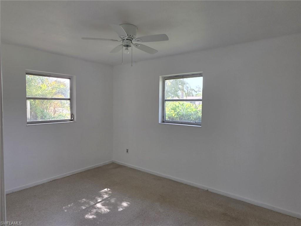 Spacious room featuring neutral carpeting, white walls, and two windows providing outdoor visibility