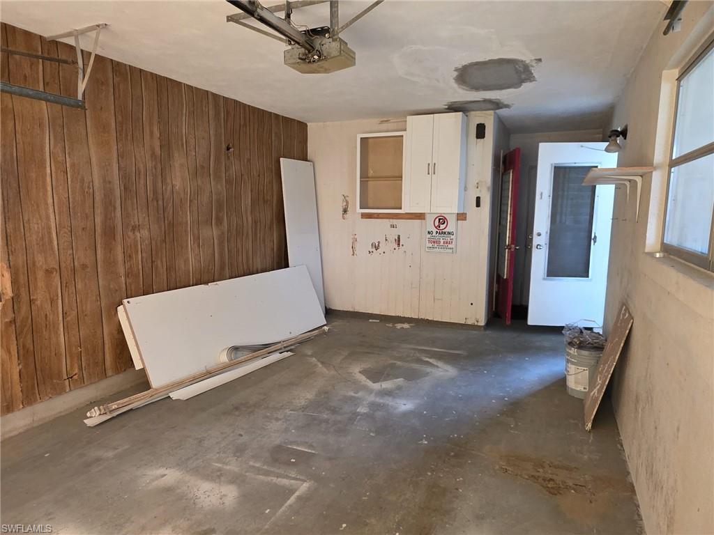 Garage space featuring a concrete floor, wood-finish paneling, and an overhead garage door opener