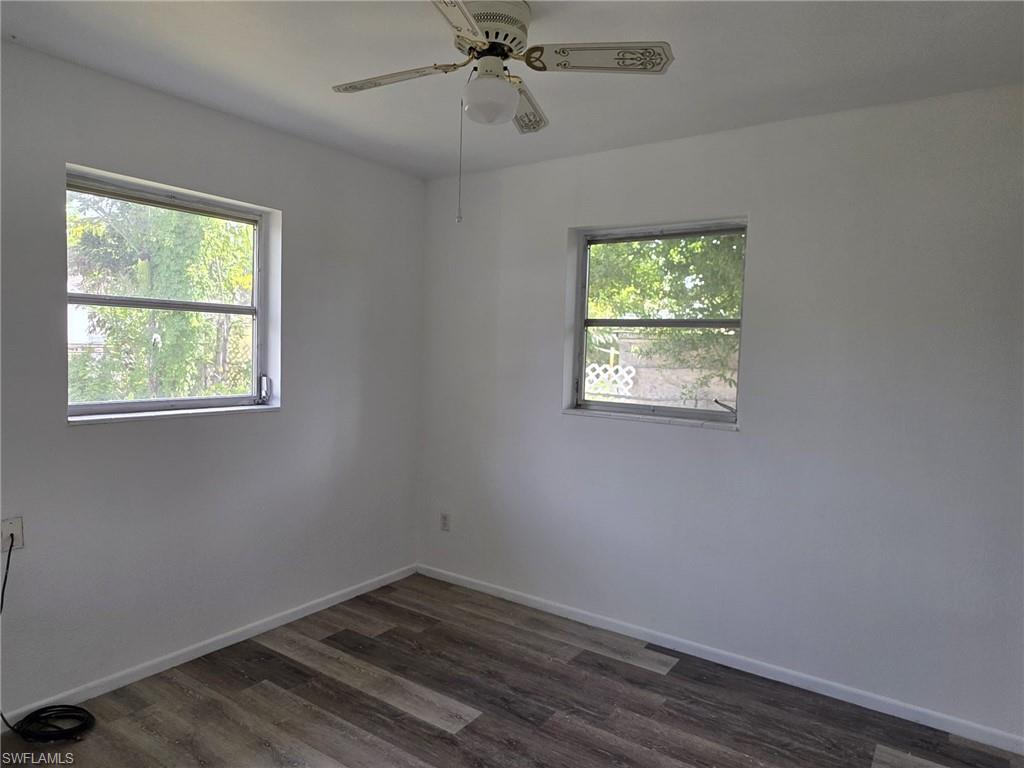 Room featuring wood-finish flooring, two windows, painted walls, and a ceiling fan with integrated lighting