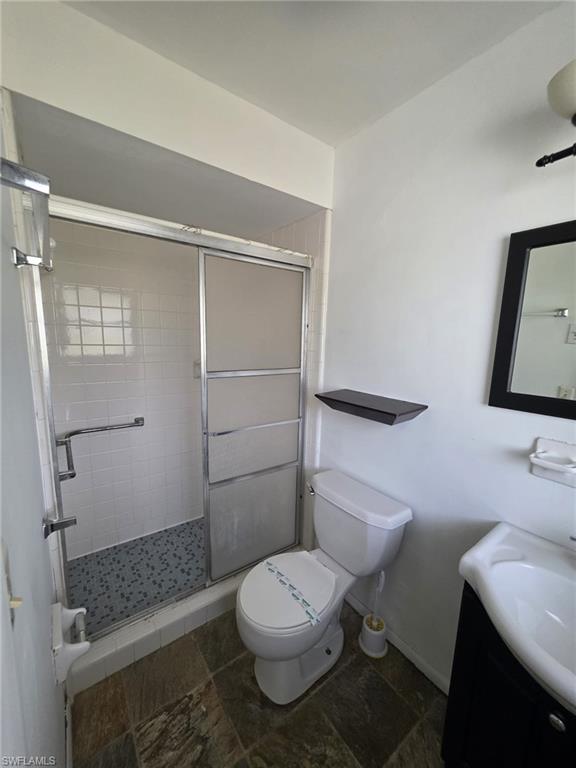 Shower enclosure with sliding frosted glass doors, white subway tile surround, and mosaic tile flooring
