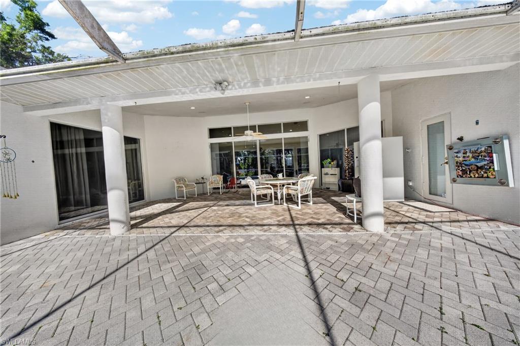Expansive outdoor patio featuring gray paver flooring, a covered veranda with recessed lighting, and multiple sliding glass doors