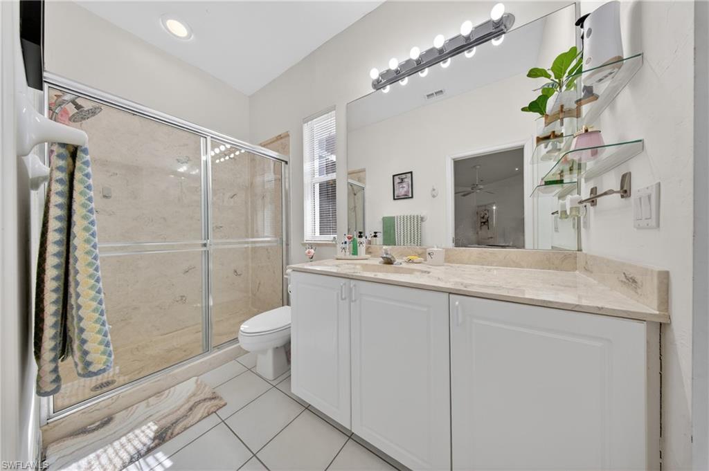 Spacious bathroom featuring a glass-enclosed shower, dual vanity with a light-toned countertop, and recessed ceiling lighting
