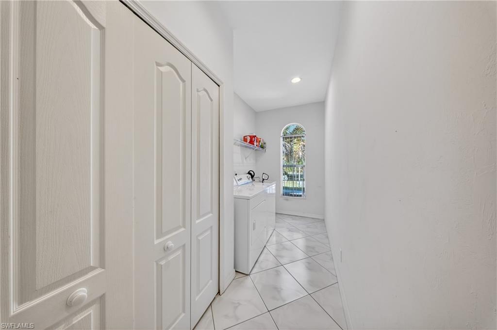 Dedicated laundry area featuring a white washer and dryer, tile flooring, an arched window, and built-in shelving