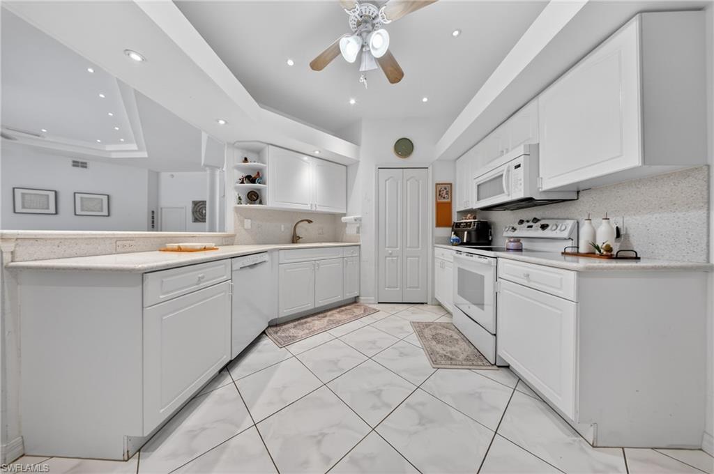 Contemporary kitchen featuring white cabinetry, light-toned countertops, and a white appliance suite