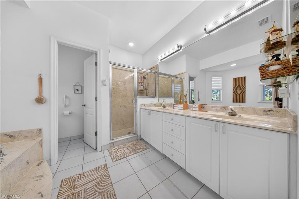 Bathroom featuring a dual vanity with light-colored countertops, white cabinetry, and a large mirror