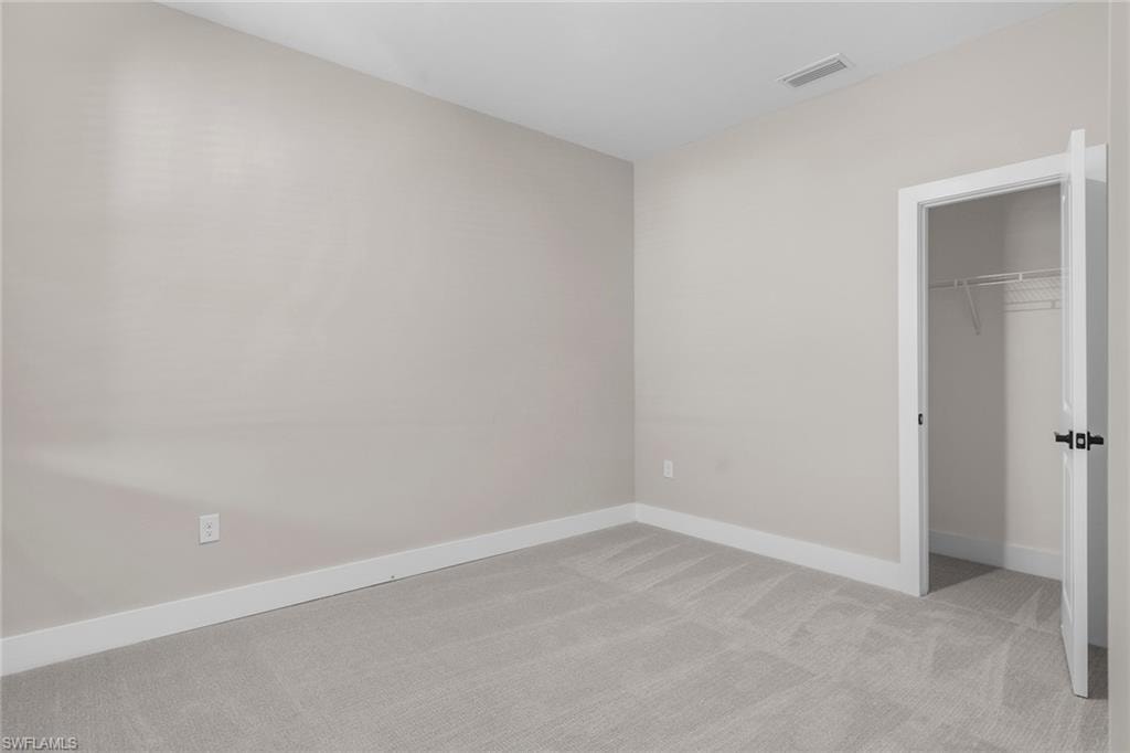 Unfurnished bedroom with light carpet and a closet