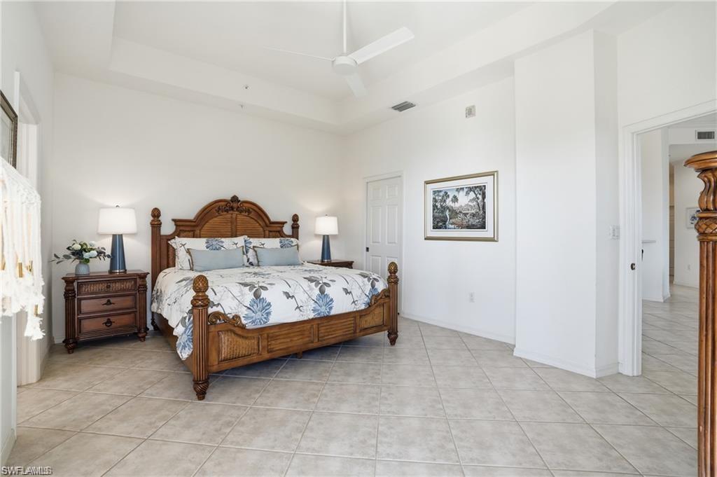 Spacious room with a tray ceiling, ceiling fan, and light-toned tile flooring