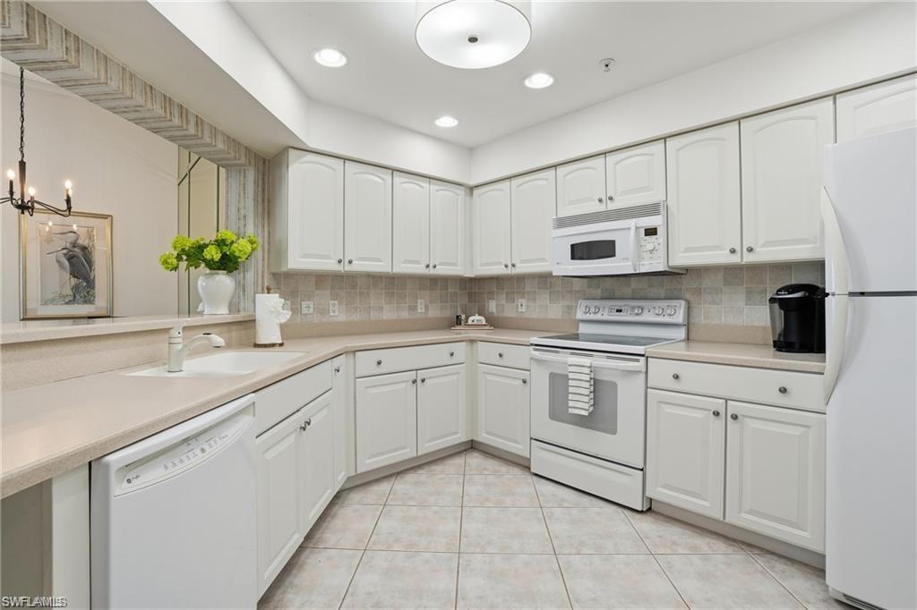 Bright kitchen featuring white cabinetry, light-toned countertops, a full tile backsplash, and tile flooring
